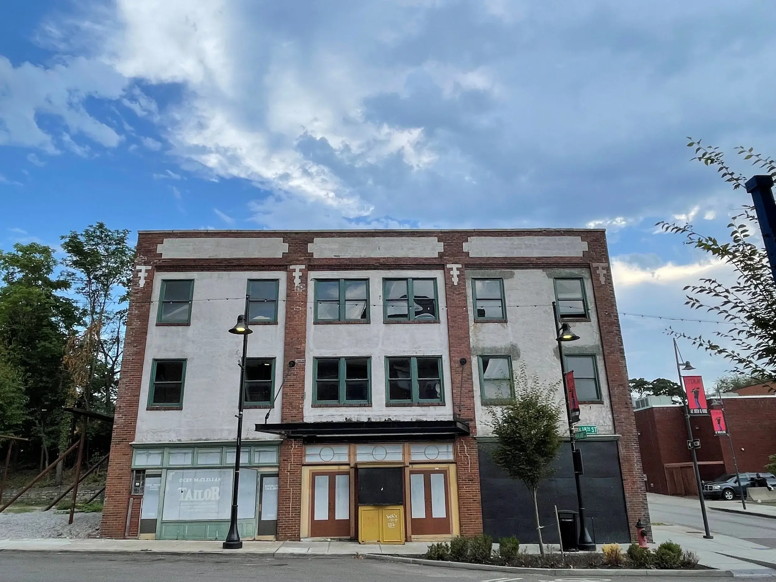 Color photo of a three story red and white brink building with yellow, black and red doors.
