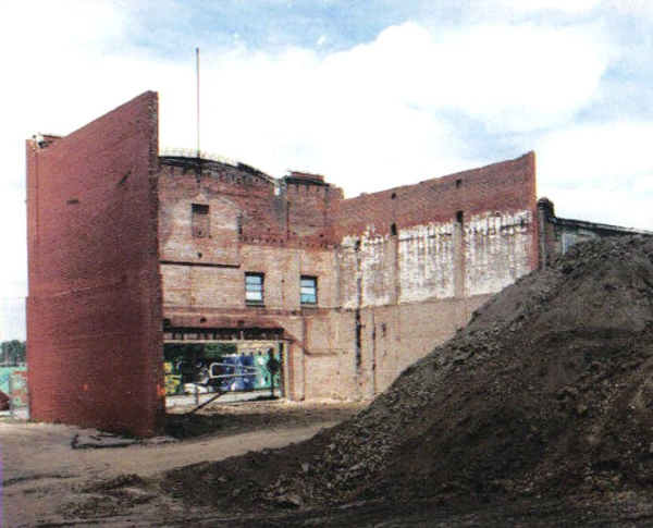 Color photo of the shell of the Gem Theater from the rear. The back wall is gone and only the sides and front remains. A large pile of dirt is in the foreground.