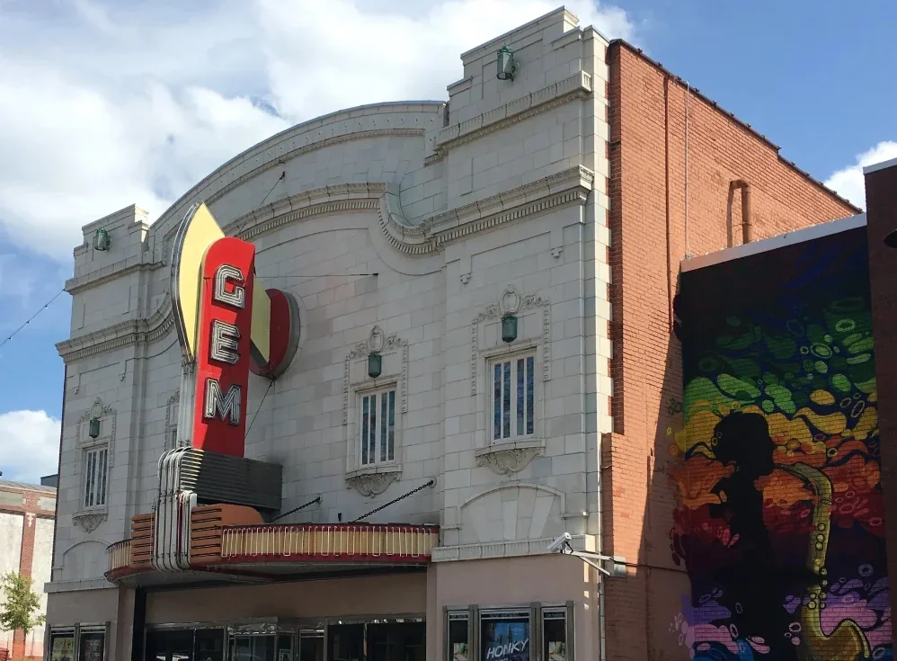 Color photo of a theater building with a large neon sign reading 