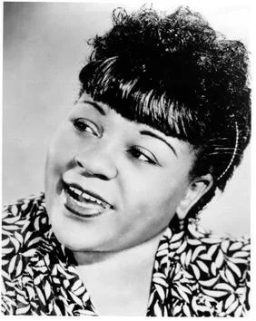 B/W portrait of a woman in a decorative blouse smiling and looking off to the side